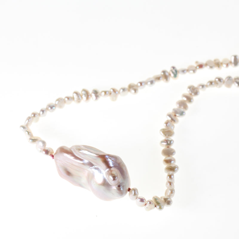 Pink hued large barque pearl strung with small seed pearls on hand knotted pink silk