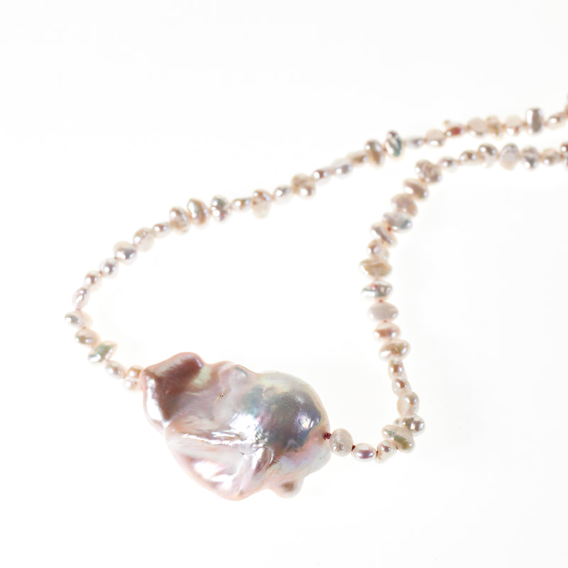 Pink hued large barque pearl strung with small seed pearls on hand knotted pink silk