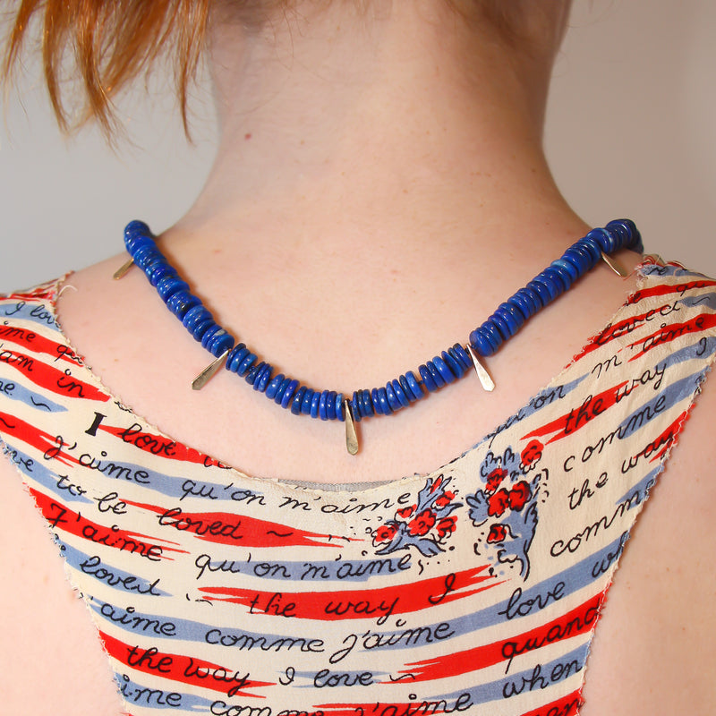 A vivid blue lapis necklace with handmade gold drops inserted between the lapis discs.