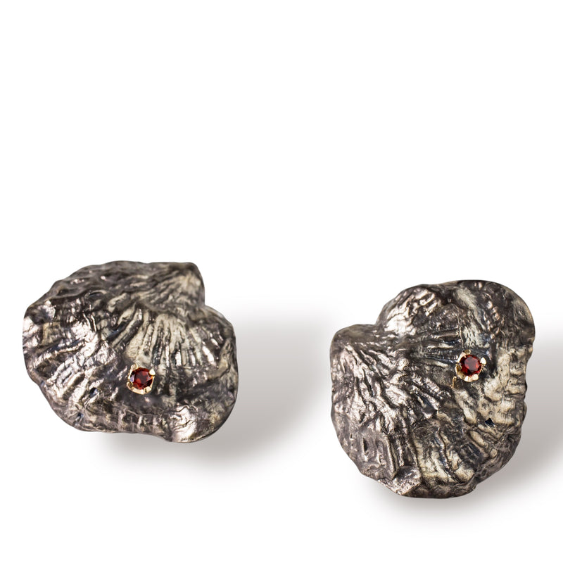 Sterling silver, 18kt gold and garnet earrings are cast from a single shell. They are large and reminiscent of an 80's power earring. Gold butterflies secure the backs. By designer Tamahra Prowse