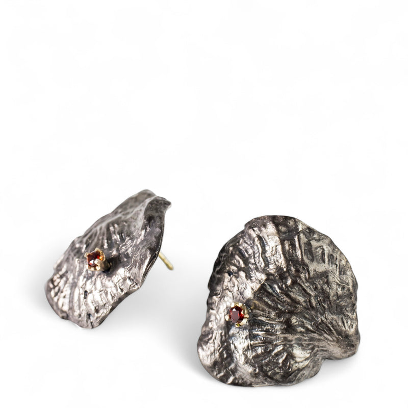 Sterling silver, 18kt gold and garnet earrings are cast from a single shell. They are large and reminiscent of an 80's power earring. Gold butterflies secure the backs. By designer Tamahra Prowse